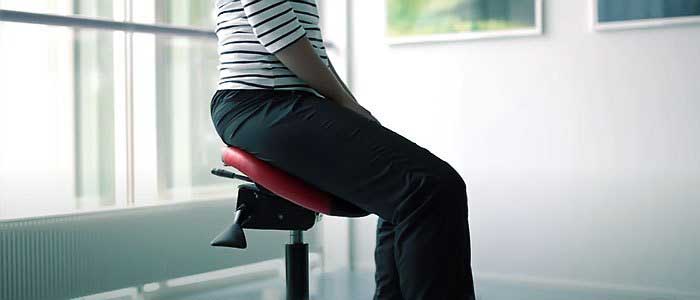 a woman sits in a saddle chair